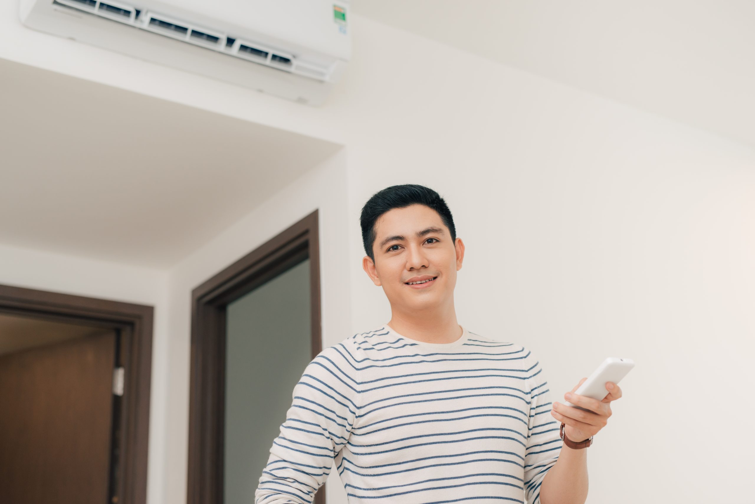 portrait happy man using remote control operate air conditioner scaled