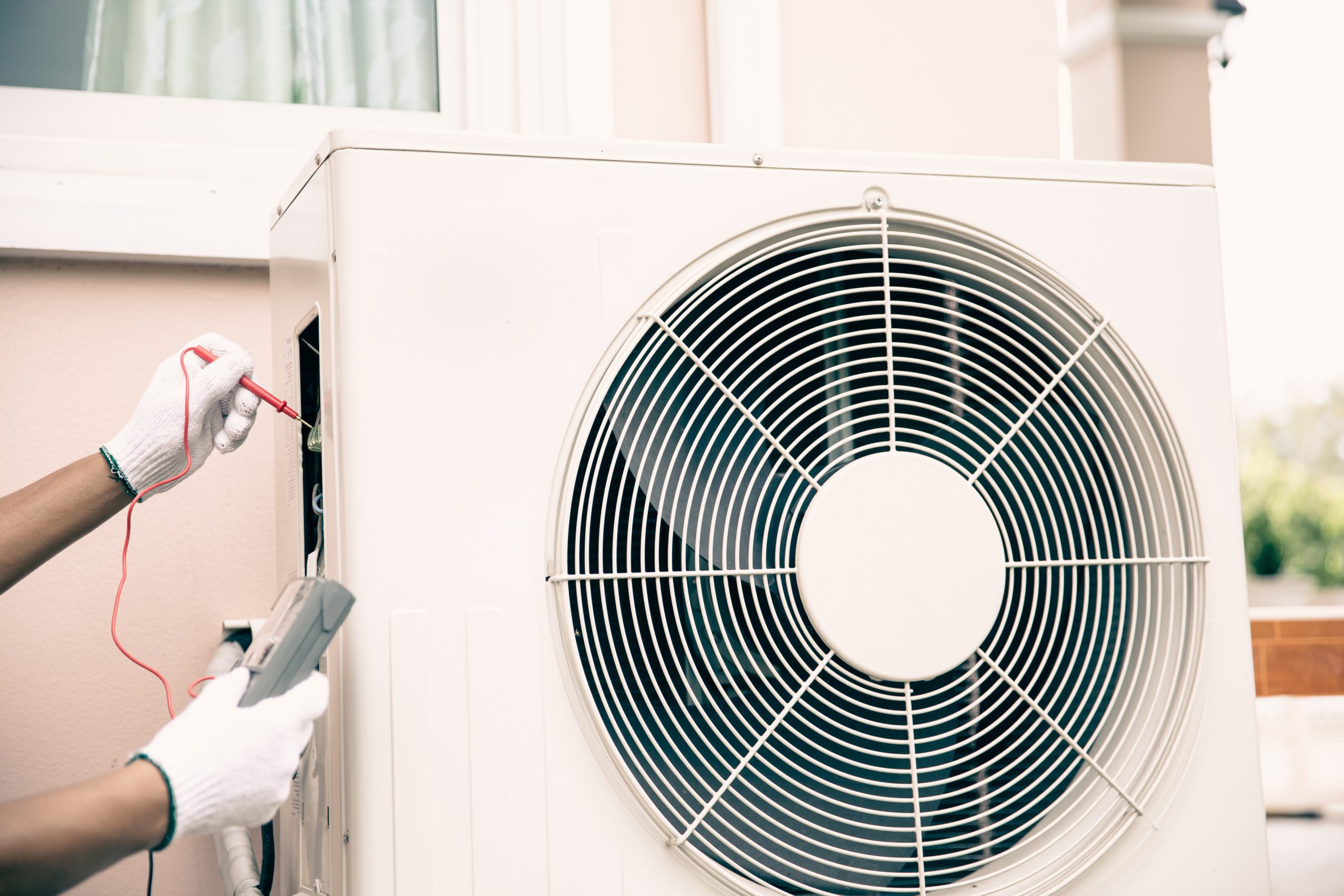 technician air conditioning repairman using measuring equipment checking electrical circuit breaker outdoor air compressor after install check refrigerant system maintenance scaled